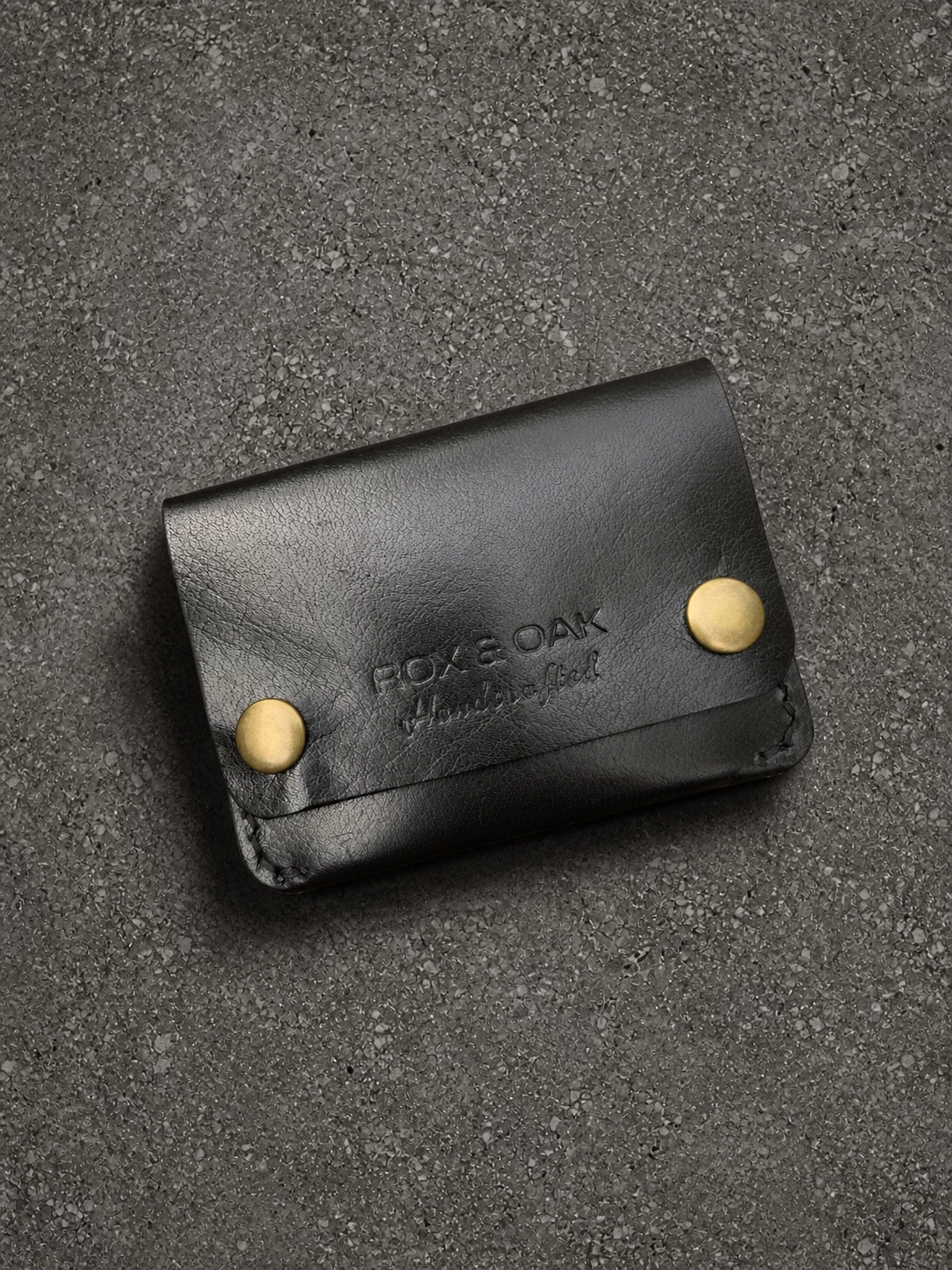Rox & Oak Terra handmade black leather card holder wallet angled flat lay with brass snap closure